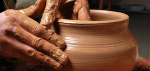 Potter's hands molding a pot