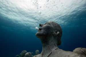 A statue breathing out air bubbles under water