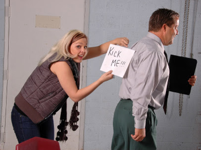 A woman holding a "kick me" sign behind a man's back