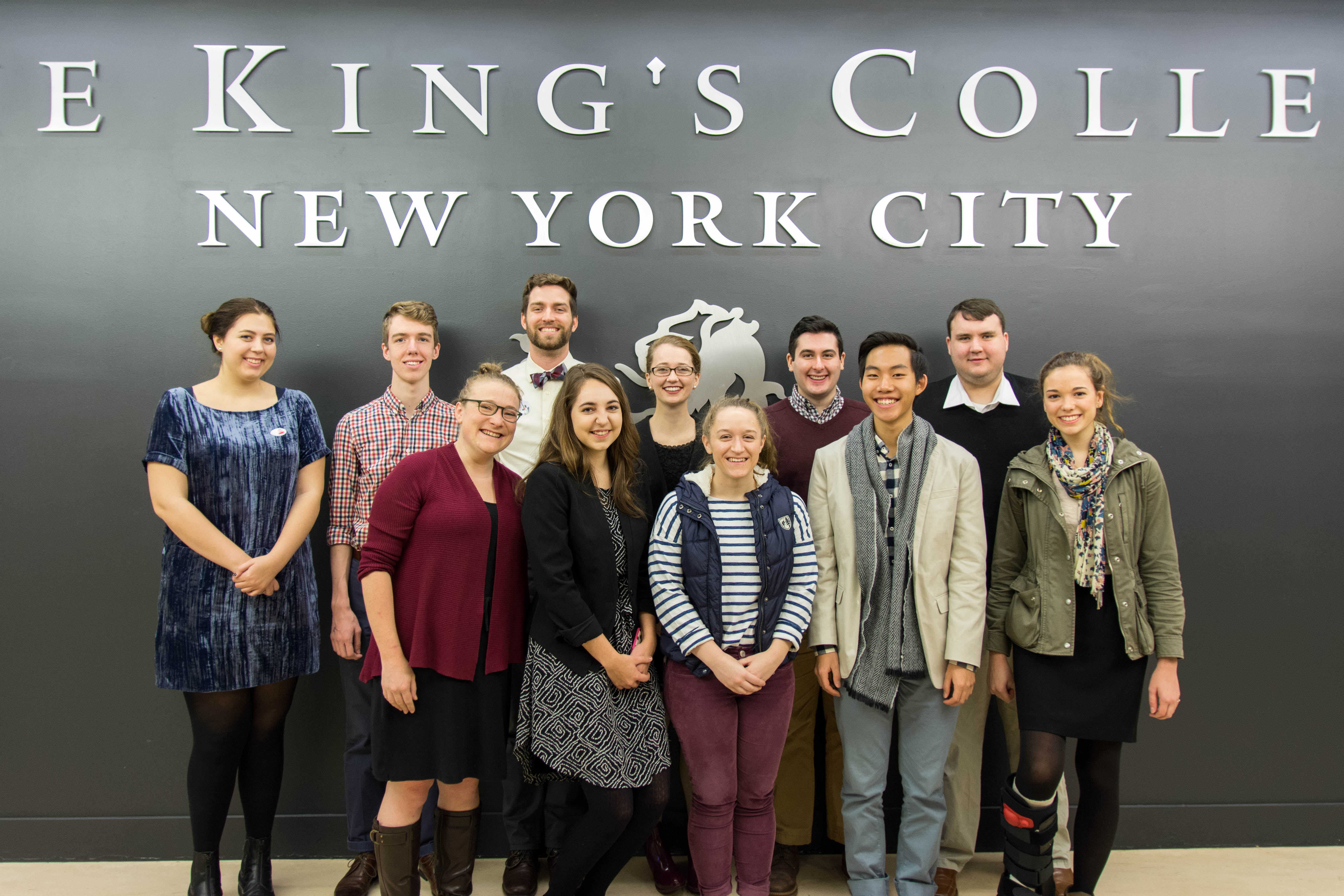 TKC Caribbean Venture team in front of TKC logo wall