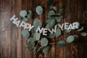 letters spelling "happy new year" on a hardwood floor w/ greenery